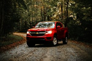 Red Chevy truck driving down a dirt Texas road