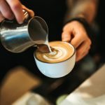 A barista prepares a latte in a coffee shop